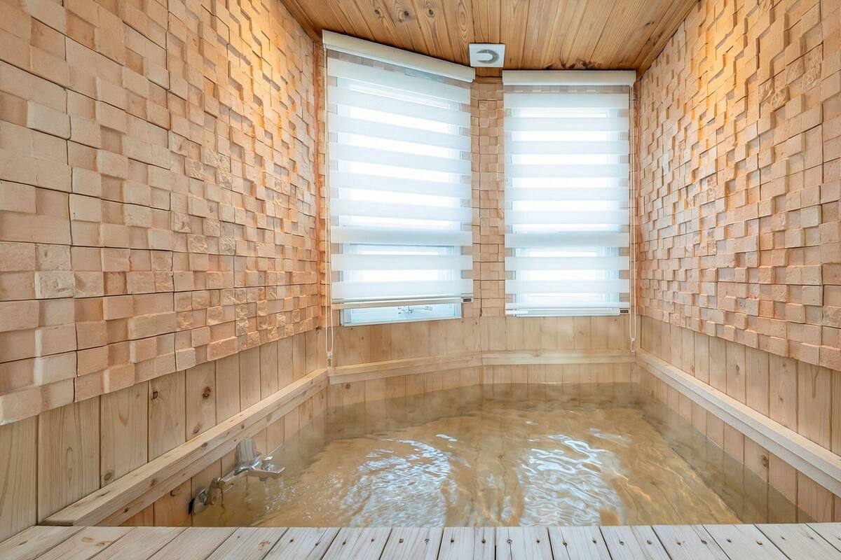 Un sauna en bois doté de deux grandes fenêtres, d’un plancher en bois et d’un mur recouvert de carreaux.