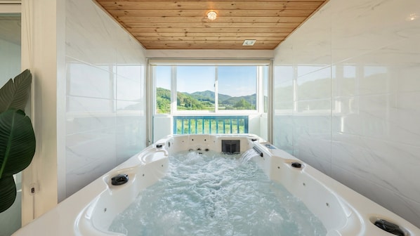 A hot tub with a view of green hills. - Gyeongju Breeze Spa Pension (Gyeongju)