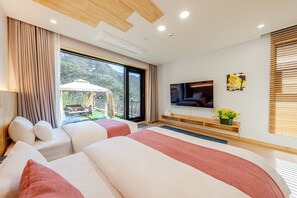 Habitación de hotel moderna con una cama grande, televisión, balcón con mobiliario exterior y vistas al exterior.