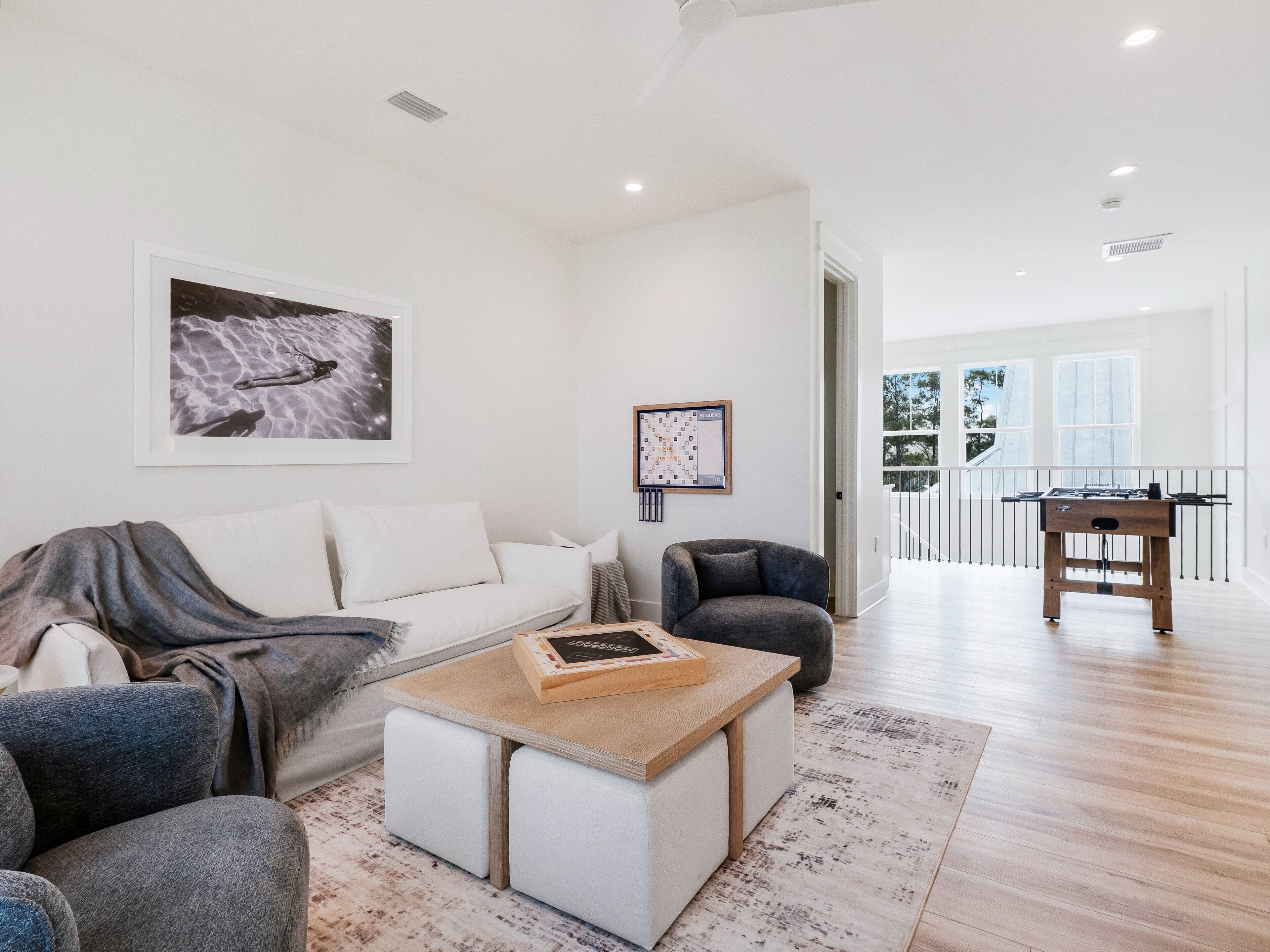 A modern living room with a sofa, armchair, coffee table, and a foosball table.