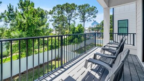 Ein Balkon mit Blick auf einen Pool, Bäume und ein Haus im Hintergrund.