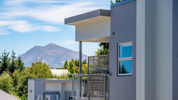A modern building with a balcony, a window, and a mountain in the background.
