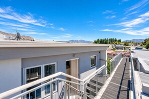 A modern building with a flat roof, satellite dishes, and a view of mountains. - Wānaka 2BR | Walk to Town | Free Parking (Wānaka)