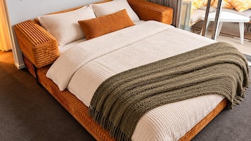 Una cama con estructura de madera, ropa de cama blanca y una manta verde.