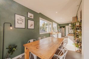 A modern kitchen with a wooden table and chairs, a built-in oven, and a plant shelf. - Family House With Hot Tub And Parking Christchurch (Christchurch)