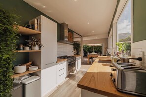 A modern kitchen with white cabinets, a wooden countertop, and a stainless steel range hood. - Family House With Hot Tub And Parking Christchurch (Christchurch)