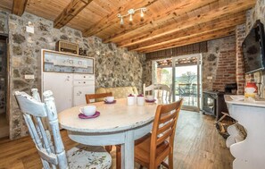 Ein rustikaler Essbereich mit Steinwand, Holzboden und einem weißen Tisch mit Stühlen.
