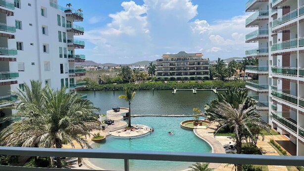 A resort with a central pool, surrounded by palm trees and modern buildings. - 🏖️☀️Hermoso condominium in Pacifika ☀️🏖️ (Mazatl án)