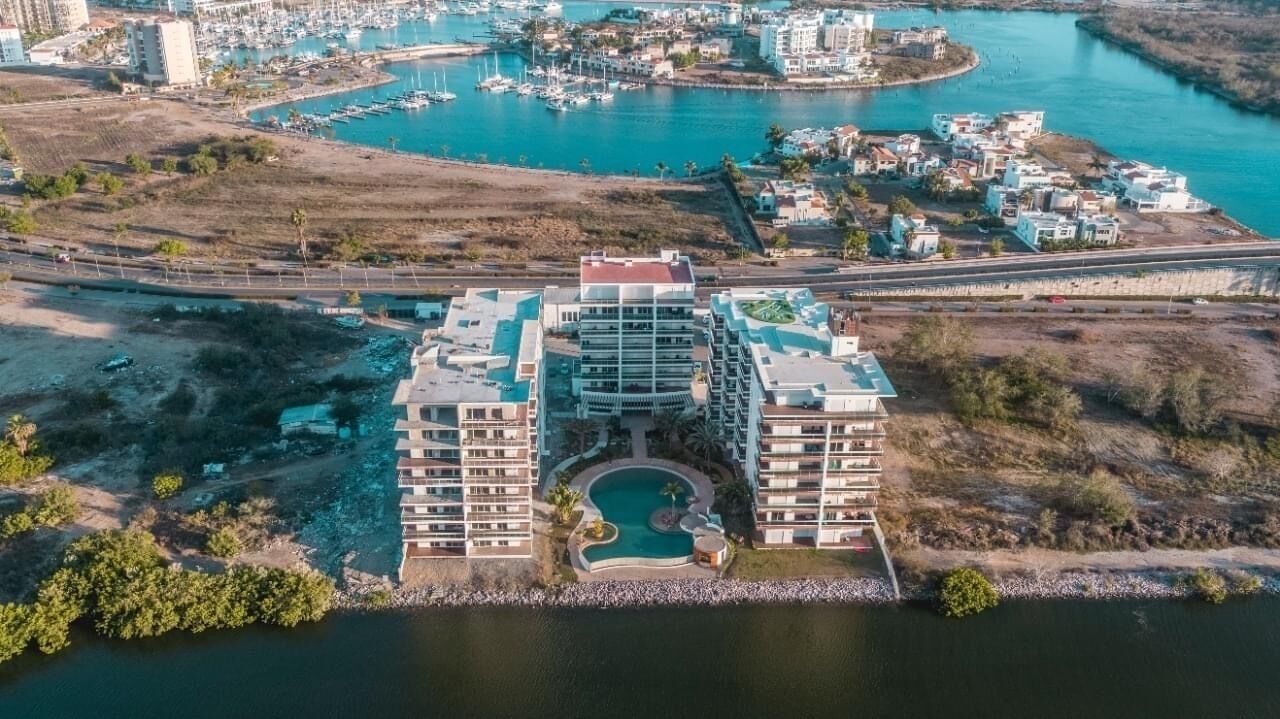 A multi-story hotel with a central courtyard and a marina in the background.