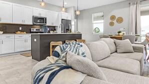 A modern kitchen with white cabinets, a central island, and pendant lighting. - Waterfront Fun, Fishing & Hot Tub Retreat for Families and Friends - Blue Heron Cottage - Roelens (Cape Coral)