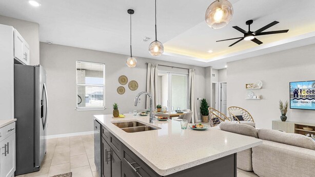 A modern kitchen with a central island, stainless steel appliances, pendant lighting, and a ceiling fan. - Waterfront Fun, Fishing & Hot Tub Retreat for Families and Friends - Blue Heron Cottage - Roelens (Cape Coral)