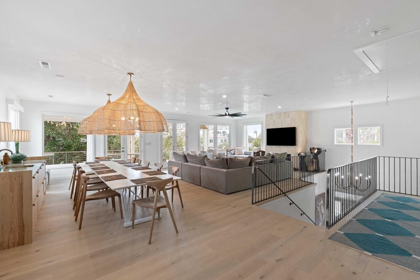 A spacious living area with a dining table, sofas, and a large hanging light fixture.
