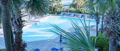 A pool area with lounge chairs and palm trees.