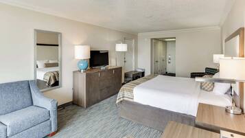 A hotel room with a bed, a desk, a chair, a television, and a wardrobe.