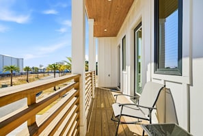 A wooden deck with a railing, a chair, and a window with blinds. - 5BR, 4.5BA Coastal Escape w/ Pool, Elevator, Near Beach & Attractions (Panama City Beach)