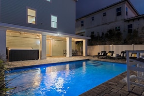 Ein Schwimmbad mit Whirlpool, Außenmöbeln und einer überdachten Terrasse.