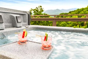 Zwei Gläser rosa Getränke mit Limette auf einer Steinoberfläche neben einem Whirlpool mit Bergblick.