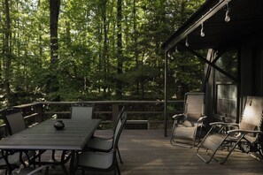 Eine Holzterrasse mit Tisch und Stühlen, umgeben von einem Wald.