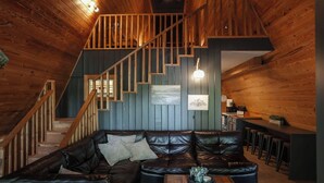 A wooden interior with a leather sofa, a staircase, and a bar area.