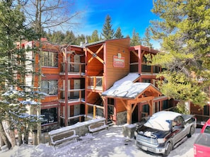 A multi-story wooden building with balconies, a covered outdoor seating area, and a sign indicating it is a lodging establishment. - CondoMooseum | 6min Walk to Main St, Riverside, Hot Tubs & Pool! (Breckenridge)