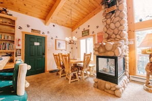 A cozy room with a stone fireplace, wooden furniture, and a green door labeled "Moose Crossing". - CondoMooseum | 6min Walk to Main St, Riverside, Hot Tubs & Pool! (Breckenridge)