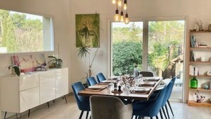 A dining area with a long table, blue chairs, and a white cabinet. - The ventabren cocoon (Nîmes)