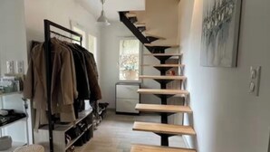 A modern interior with a wooden staircase, a clothing rack, and a desk area. - The ventabren cocoon (Nîmes)
