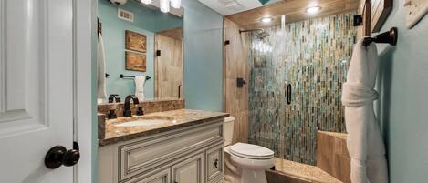 Une salle de bain équipée d’une douche, de toilettes et d’un meuble-lavabo avec un miroir.