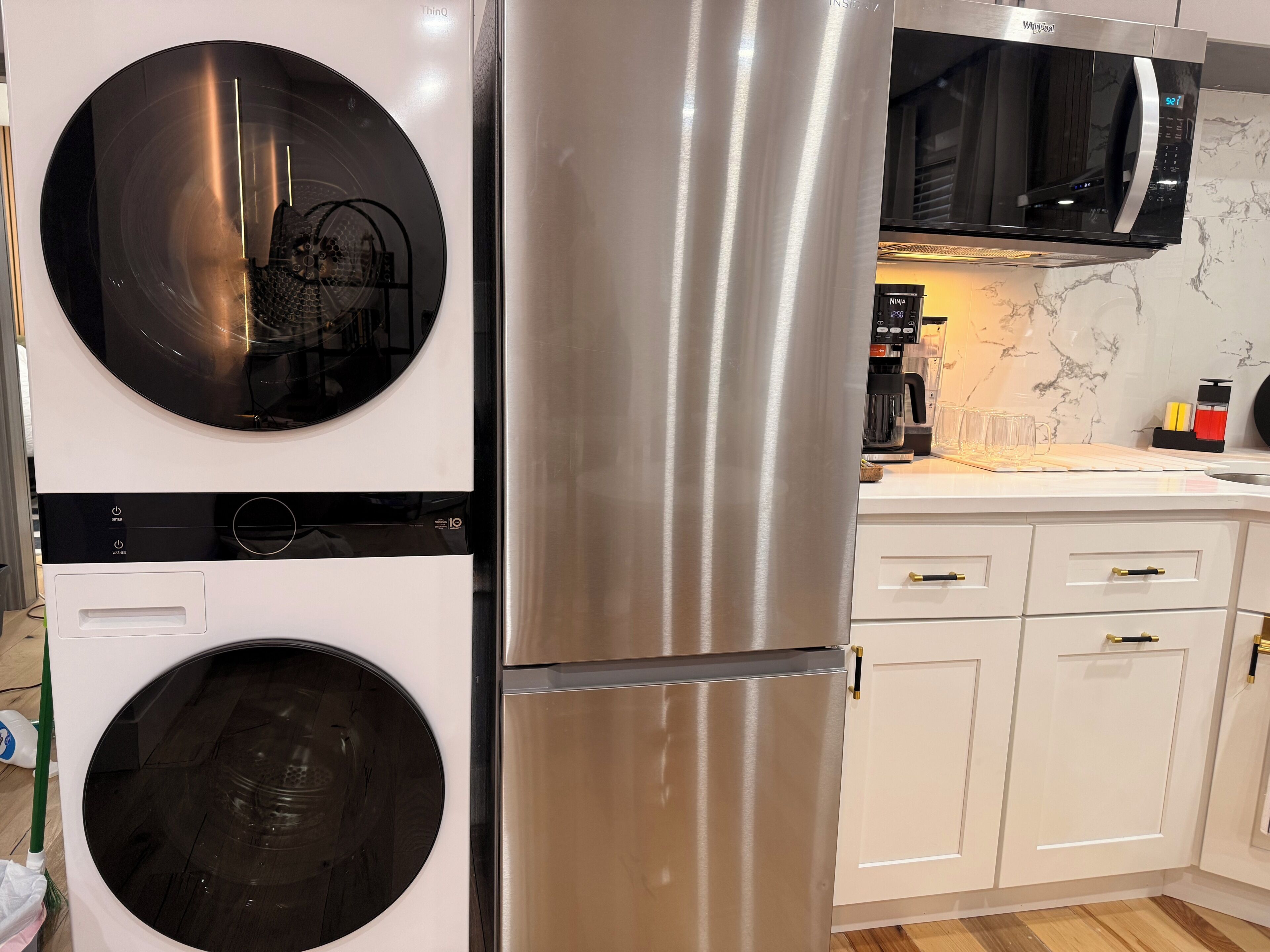 A kitchen with a stainless steel refrigerator, a washing machine, and a microwave.