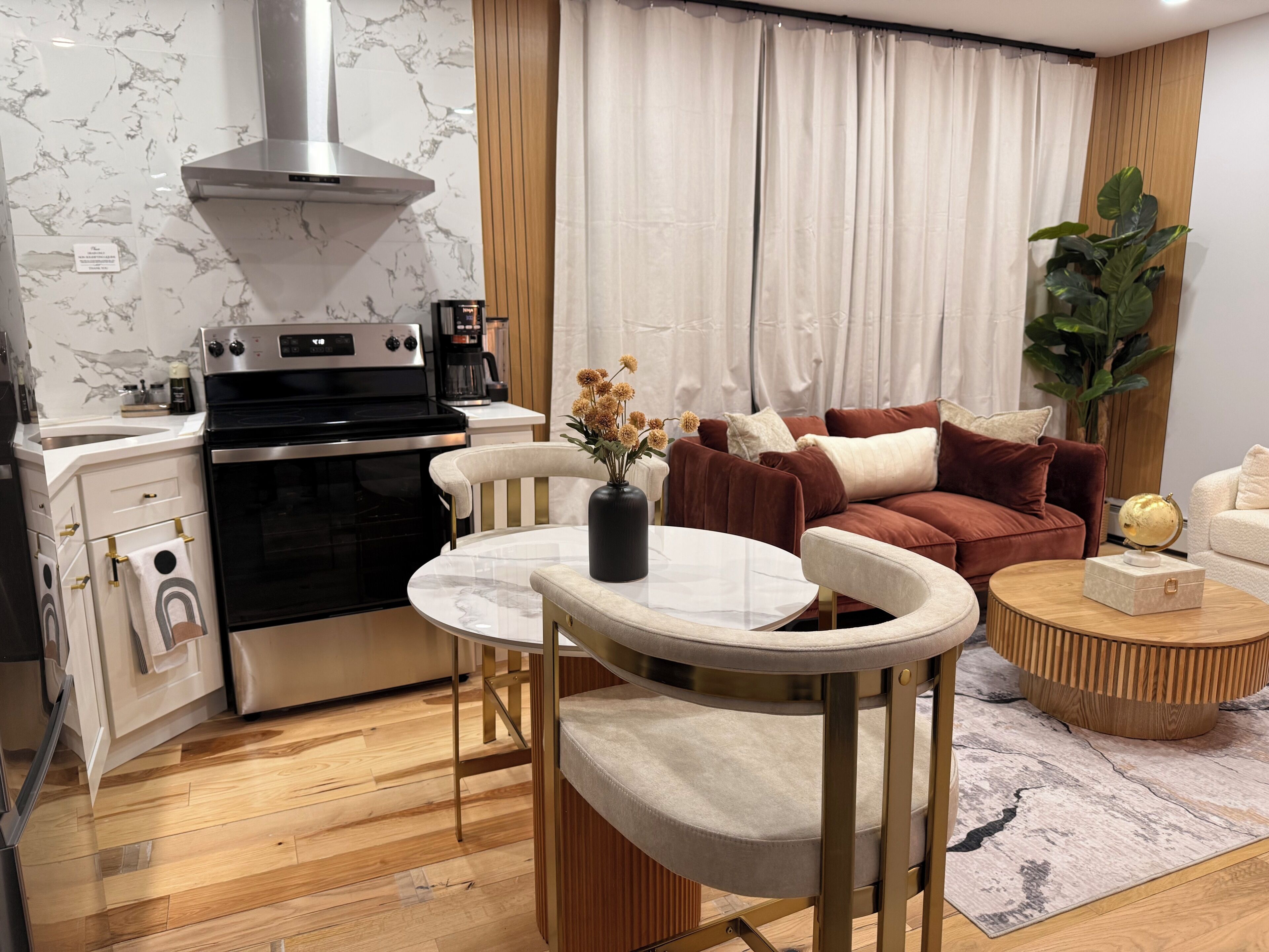 A modern kitchen with a stove, oven, and a dining area with a table and chairs.