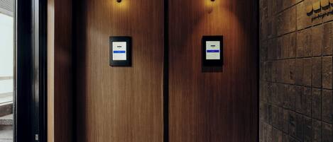 A hotel entrance with a double door, a security camera, and a digital display on the wall.