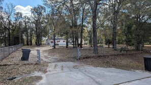 Ein Campingplatz mit befestigtem Weg, einem eingezäunten Bereich und einem Mobilheim im Hintergrund.