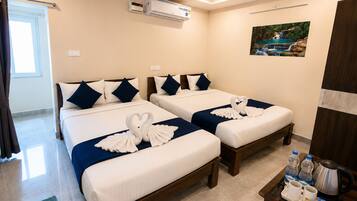 A hotel room with two beds, a painting on the wall, an air conditioning unit, and a tray table with toiletries.