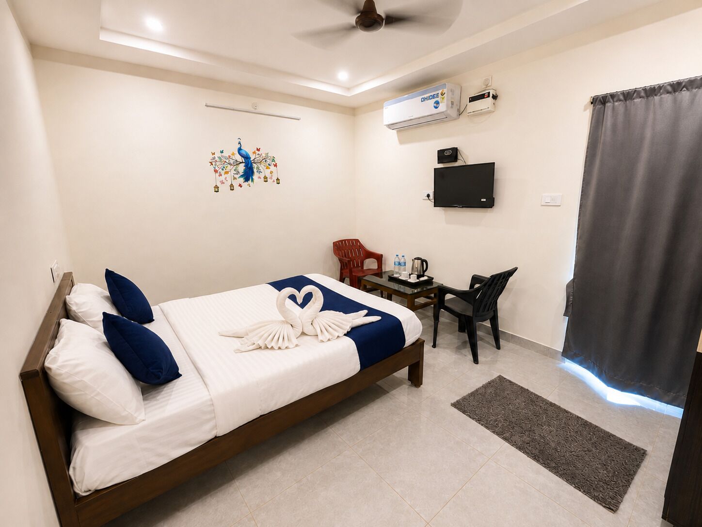 Une chambre d’hôtel équipée d’un lit, d’un bureau, d’une chaise, d’un téléviseur à écran plat, d’un climatiseur et d’un élément décoratif mural.