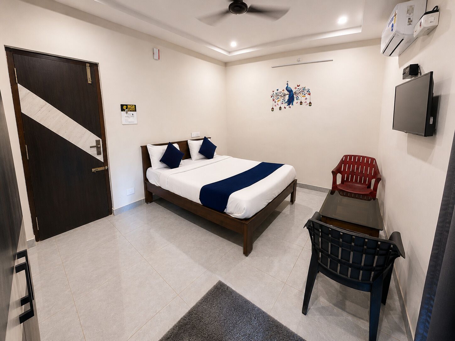 Een hotelkamer met een bed, bureau, stoel, televisie en een deur.