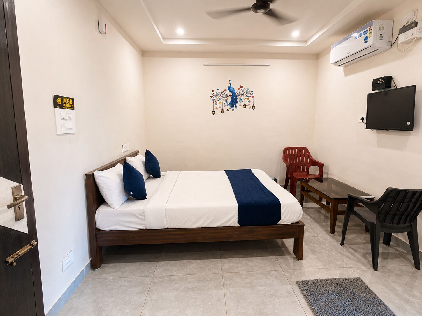 Un dormitorio con cama, escritorio, silla, aire acondicionado y televisor.