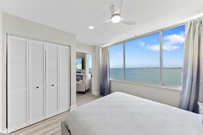 Ein Schlafzimmer mit einem großen Bett, einem Deckenventilator, Meerblick und einem begehbaren Kleiderschrank.