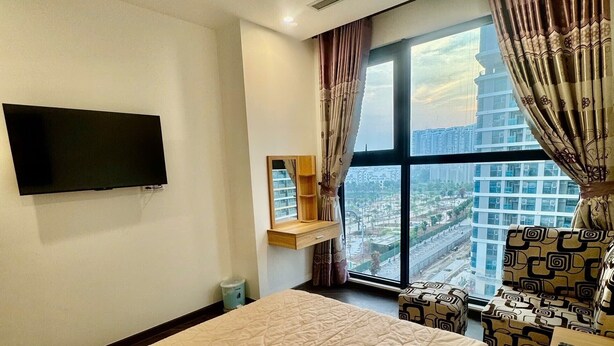 Une chambre d’hôtel avec un grand lit, un téléviseur à écran plat fixé au mur, une fenêtre avec des rideaux et une vue sur la ville.
