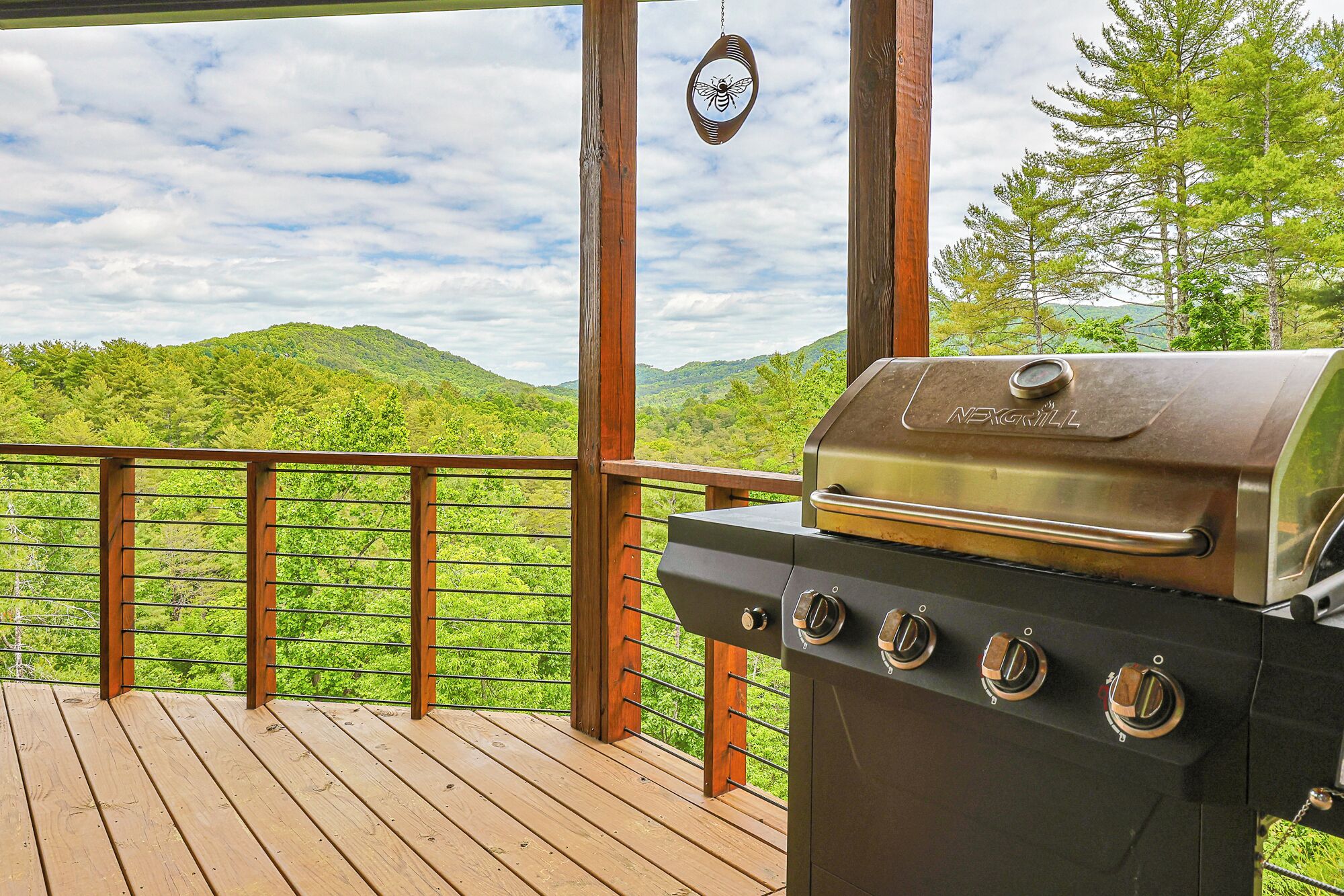 A wooden deck with a grill and a hanging insect repellent.