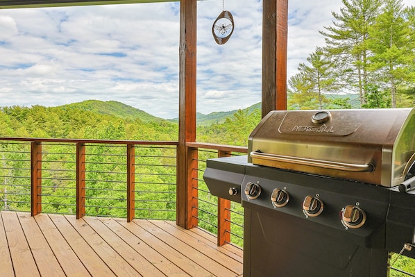 Une terrasse en bois avec un barbecue et un dispositif anti-insectes suspendu.