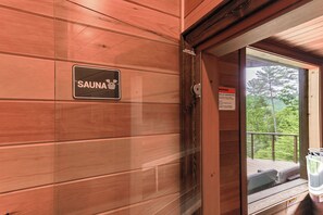 A wooden wall with a sign indicating a sauna, a door, and a balcony with outdoor furniture. - Honey Bear Lodge  a peaceful mountain getaway with spa-style accommodations! (Blue Ridge)