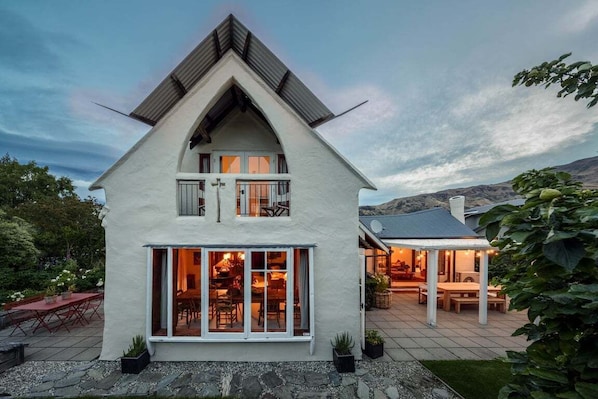 Ein zweistöckiges Haus mit geneigtem Dach, großen Fenstern und einer Terrasse.