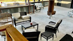 Un espace extérieur abrité, aménagé avec des meubles en osier, un banc en bois et une table en métal.