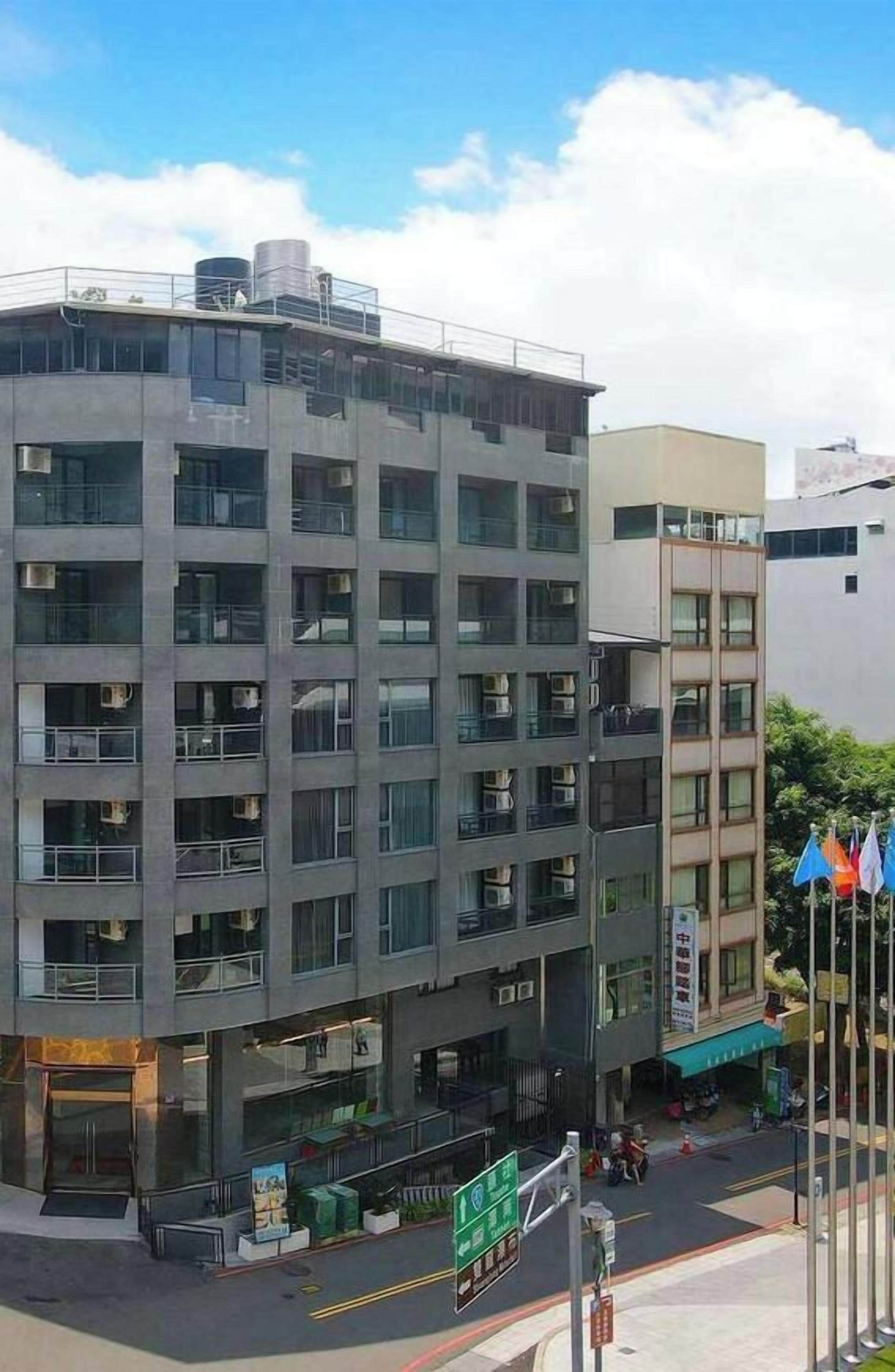 A multi-story building with a ground-level commercial space, large windows, and a flat roof.