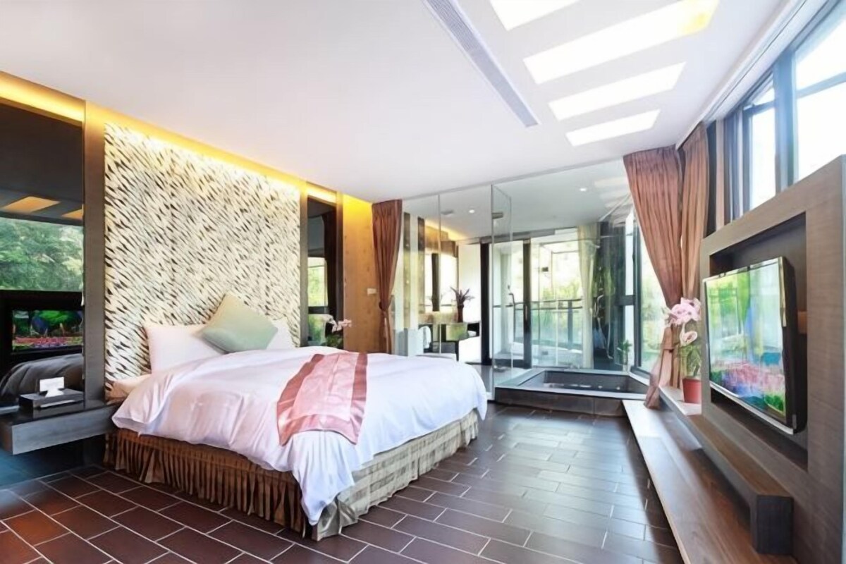 Une chambre d’hôtel moderne dotée d’un grand lit, d’une télévision et offrant une vue sur l’extérieur.