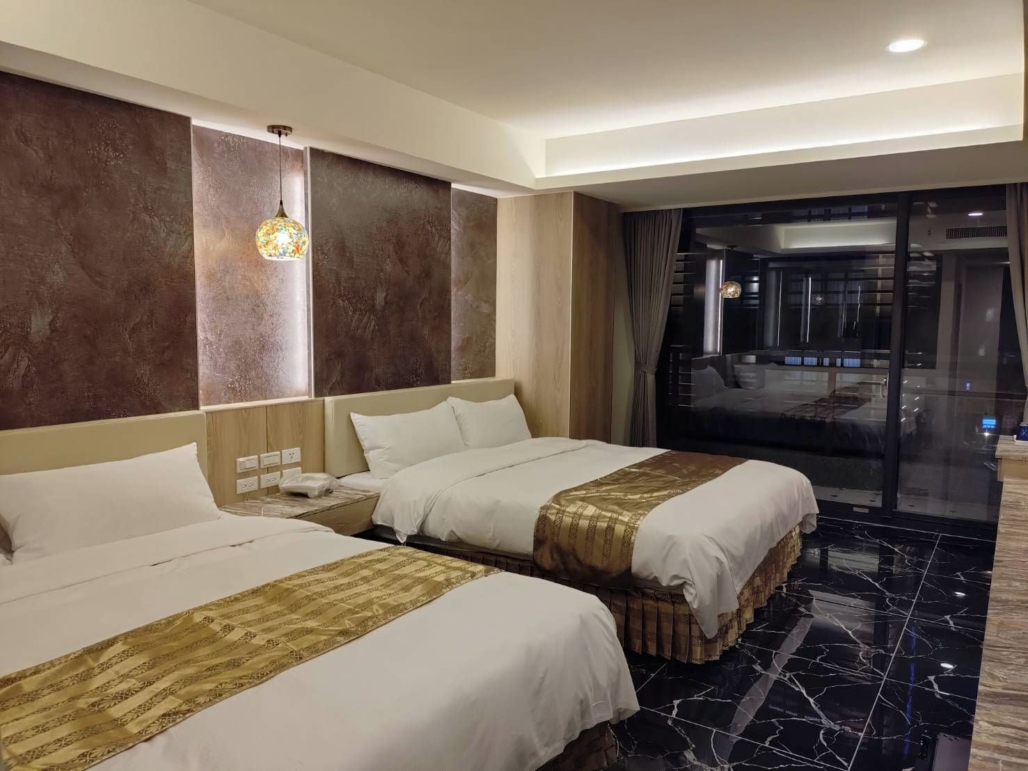 A hotel room with two beds, a large window, and a view of the city.