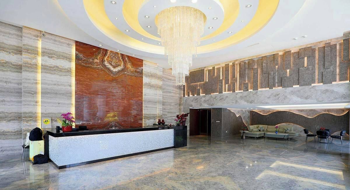A modern lobby with a reception desk, a large abstract mural, a chandelier, and a seating area with sofas.