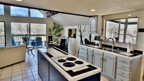 Una cocina moderna con una isla central, ventanas amplias y una zona de comedor con sofá.