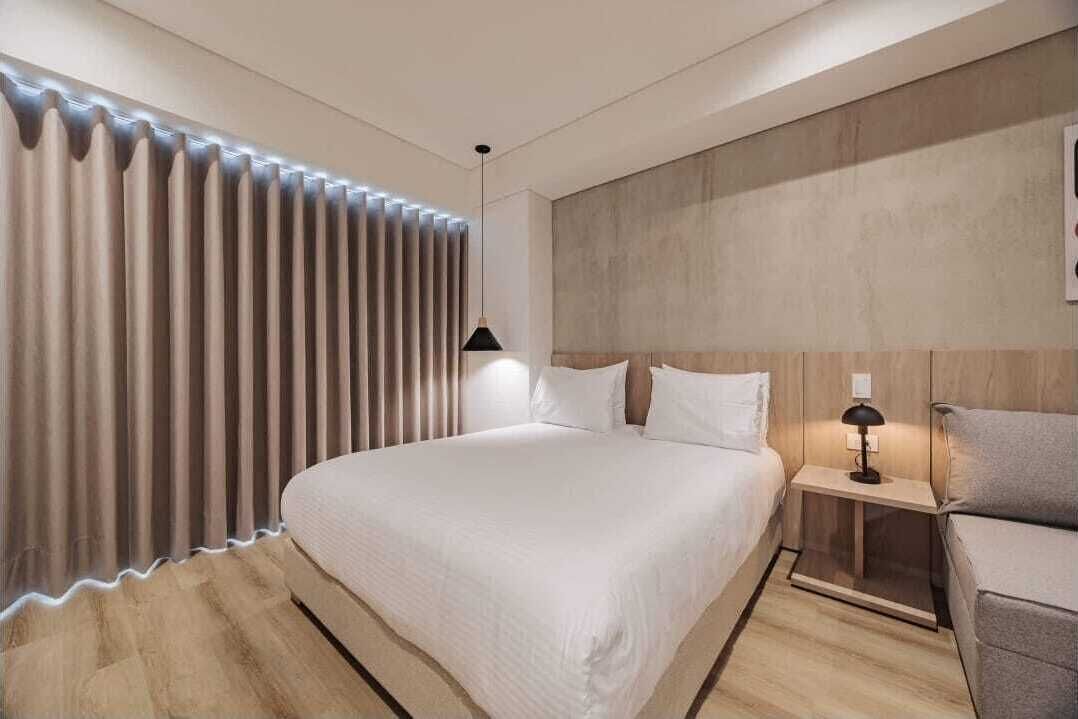 Une chambre à coucher moderne avec un grand lit, une table de chevet avec une lampe et une tête de lit adossée à un mur à texture.