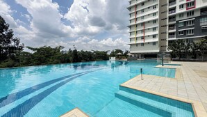 A swimming pool with clear blue water, surrounded by a tiled deck and a multi-story building with balconies. - Residensi Suasana Damai by Airhost (Sungai Buloh)
